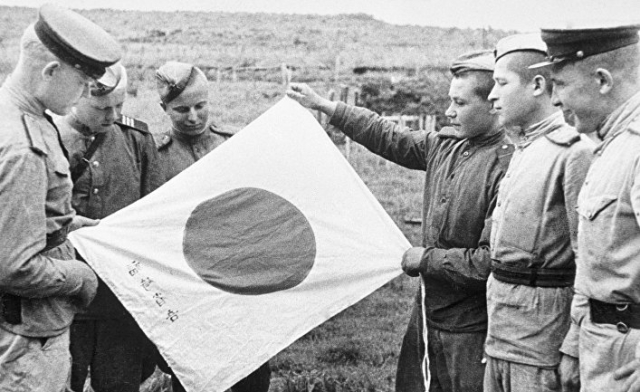 Красноармейцы рассматривают брошенный при отступлении японский флаг. 1945