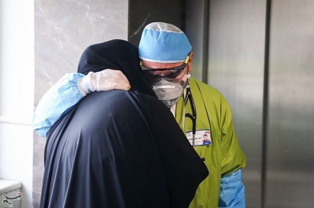 Иранский врач утешает родственников пациента, умершего от COVID-19
