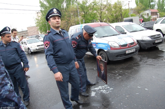 Полицейский поднимает фотографию Сержа Саргсяна