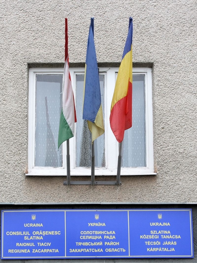 Флаги и таблички на поселковом совете Солотвины- венгерские, украинские, румынские флаги и надписи 