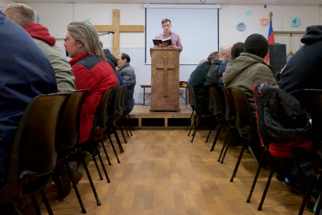 Алтарник Игорь Павлов читает проповедь бездомным. Волонтеры Анненкирхе участвуют в программе по кормлению бездомных, помогая питерской̆ «Армии Спасения»