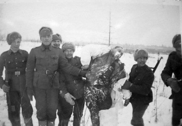 Финские военнослужащие позируют рядом с телом замерзшего красноармейца. 1939