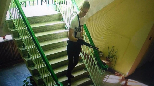 Подозреваемый Владислав Росляков, вооружённый ружьём, спускается по лестнице в здании колледжа. Керчь
