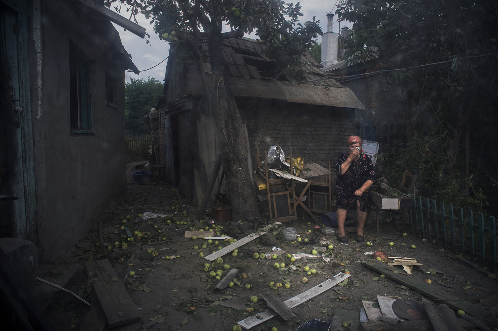 Пожилая женщина во дворе своего дома после обстрела. Луганск, Украина