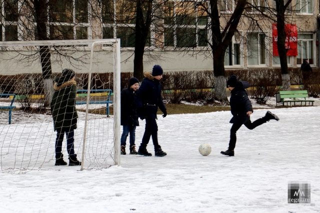 Дети играют в футбол на школьном стадионе 