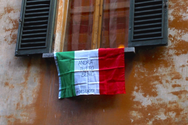 Вывешенный из окна флаг Италии с надписью «Andrà tutto bene» (Все будет хорошо)