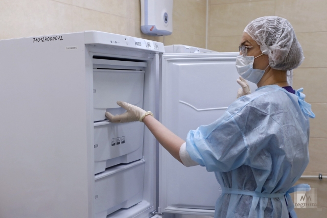 Медсестра достаёт из морозильника вакцину от коронавируса