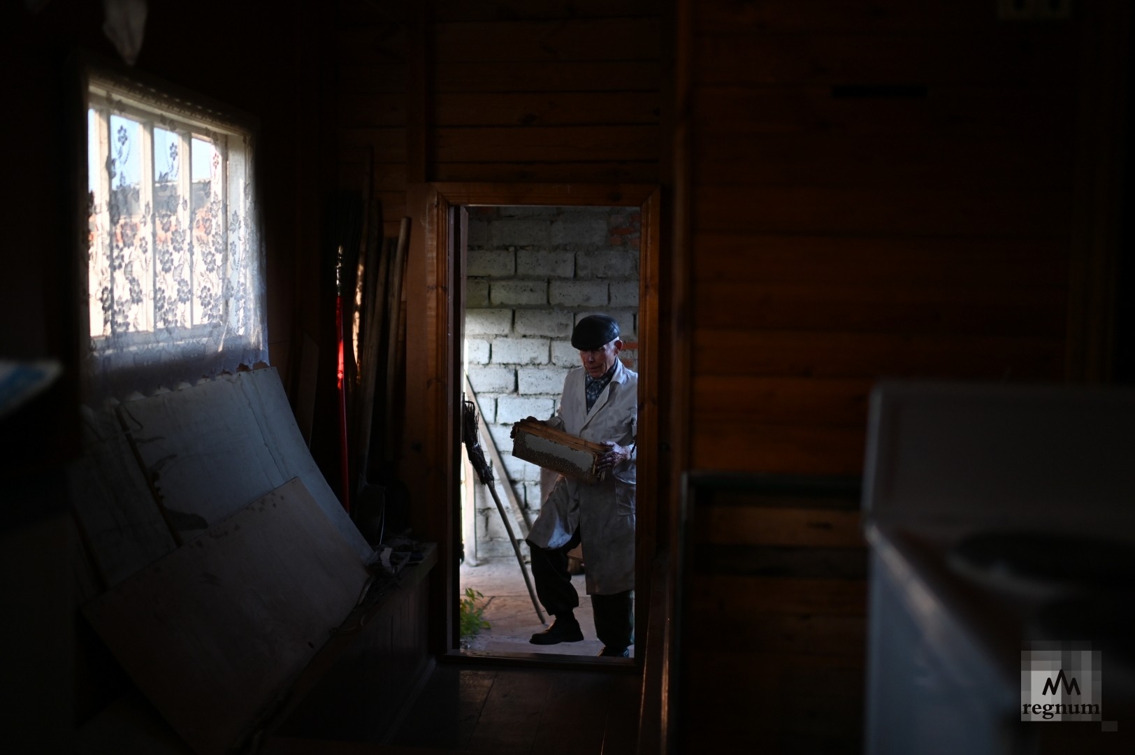 Алексей Михайлович несёт полные меда рамки на откачку у себя дома