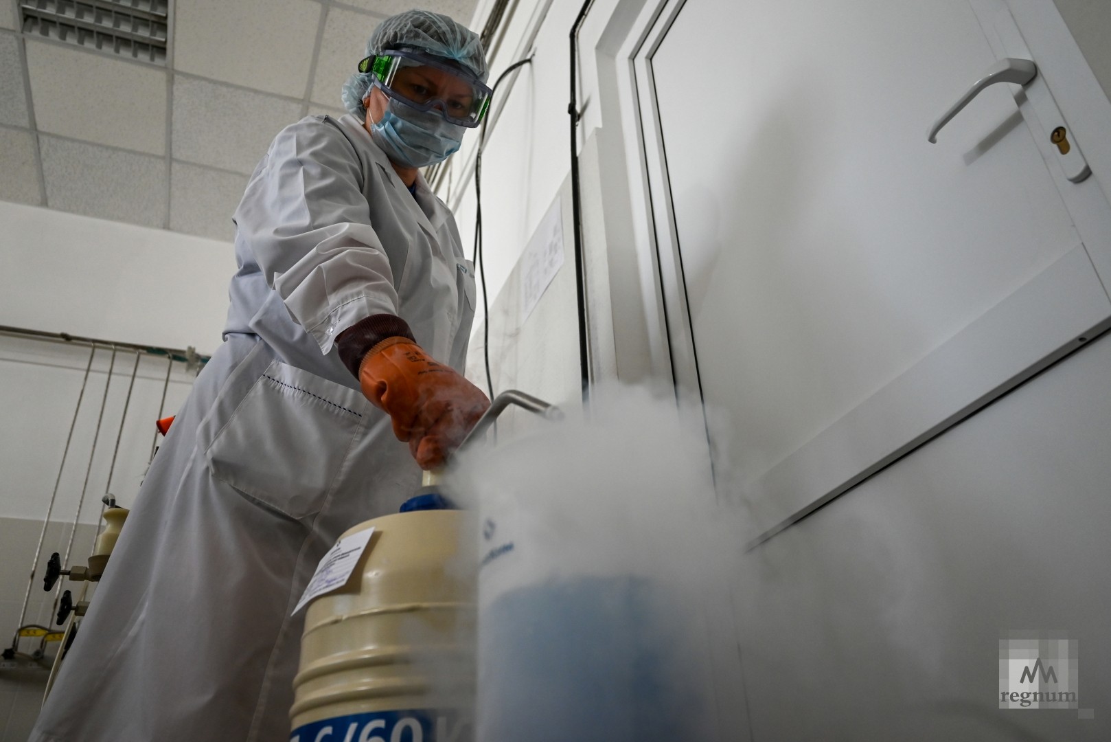 Работник лаборатории наполняет ёмкость жидким медицинским кислородом, взятым для определения количества кислорода