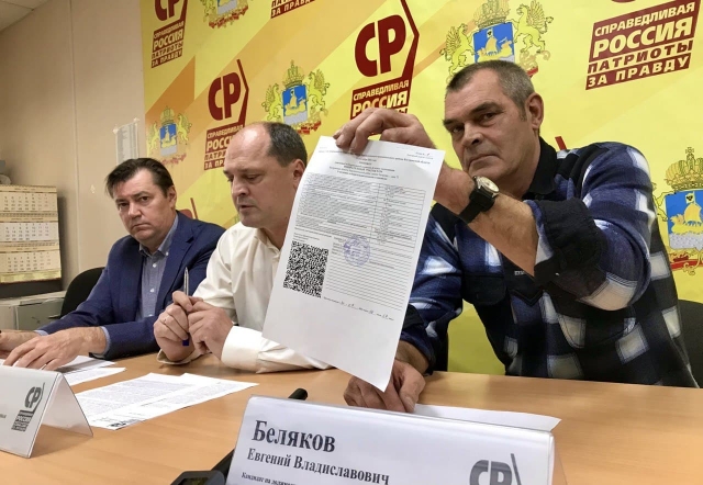 Кандидат Беляков показывает повторный протокол на пресс-конференции
