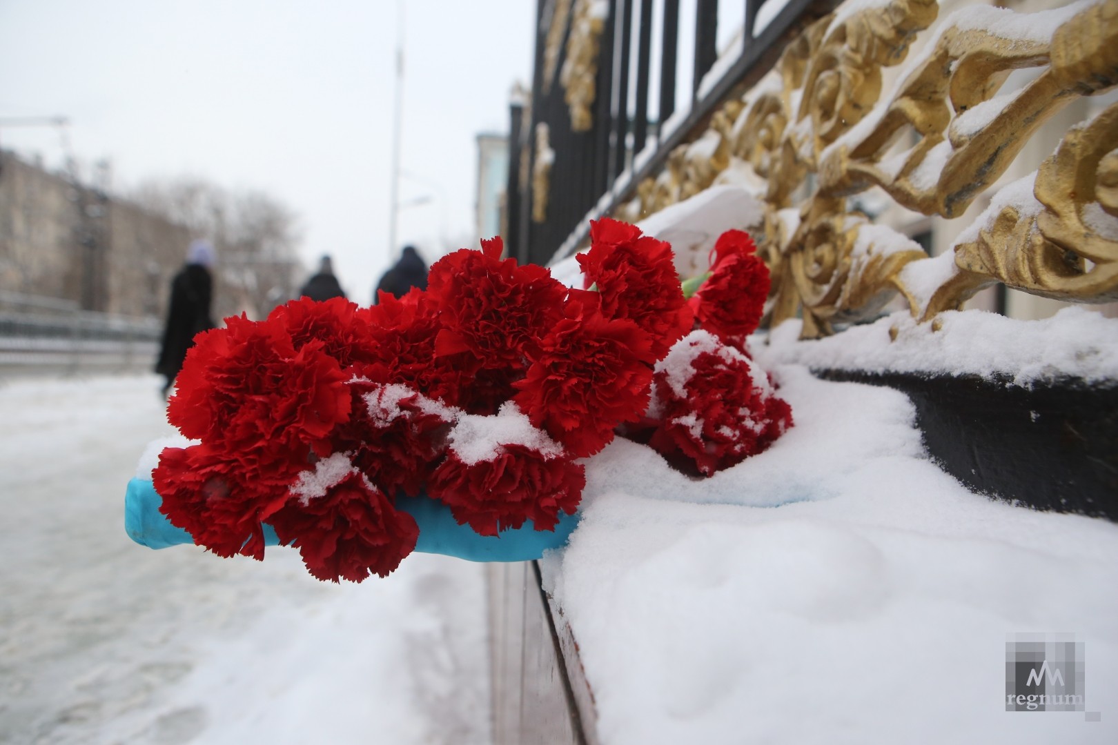 Люди несут цветы к посольству Казахстана