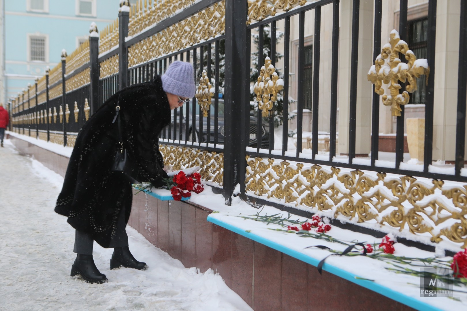 Люди несут цветы к посольству Казахстана