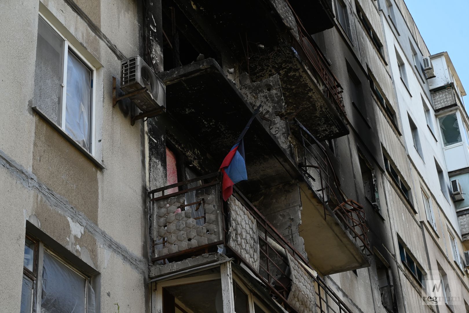 Флаг ДНР в окне пострадавшего от обстрелов жилого дома